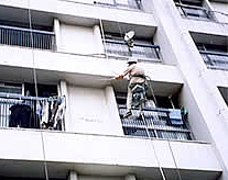 マンションの外壁をハンバーで叩いて調査する男性